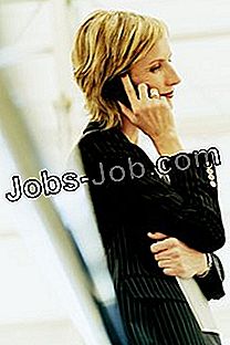 Изглед отстрани на зрял, женски изпълнителен директор, облегнат на парапет и използвайки мобилния си телефон